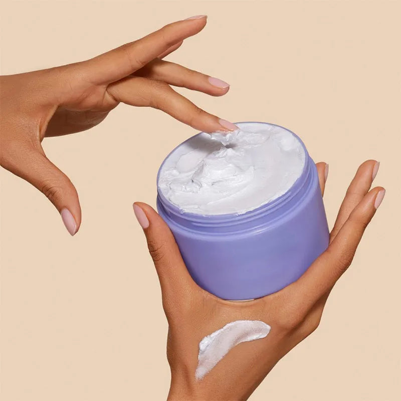 MenoMode firming skin cream for menopause in a purple jar being applied by hand with smooth creamy texture
