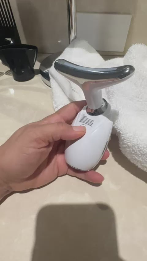 Hand holding DC-eterus LED therapy device for skin tightening with white towel and sink background