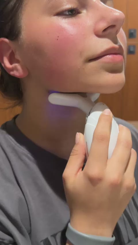 Woman using DC-eterus LED therapy device for skin tightening on her neck