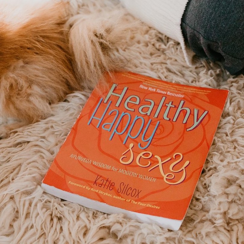 Healthy Happy Sexy book by Katie Silcox offering wellness tips for women over 40 on a soft surface