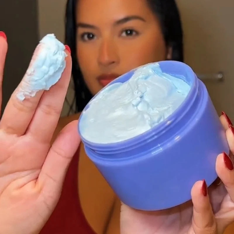 MenoMode firming skin cream for menopause in a blue jar with cream on fingers