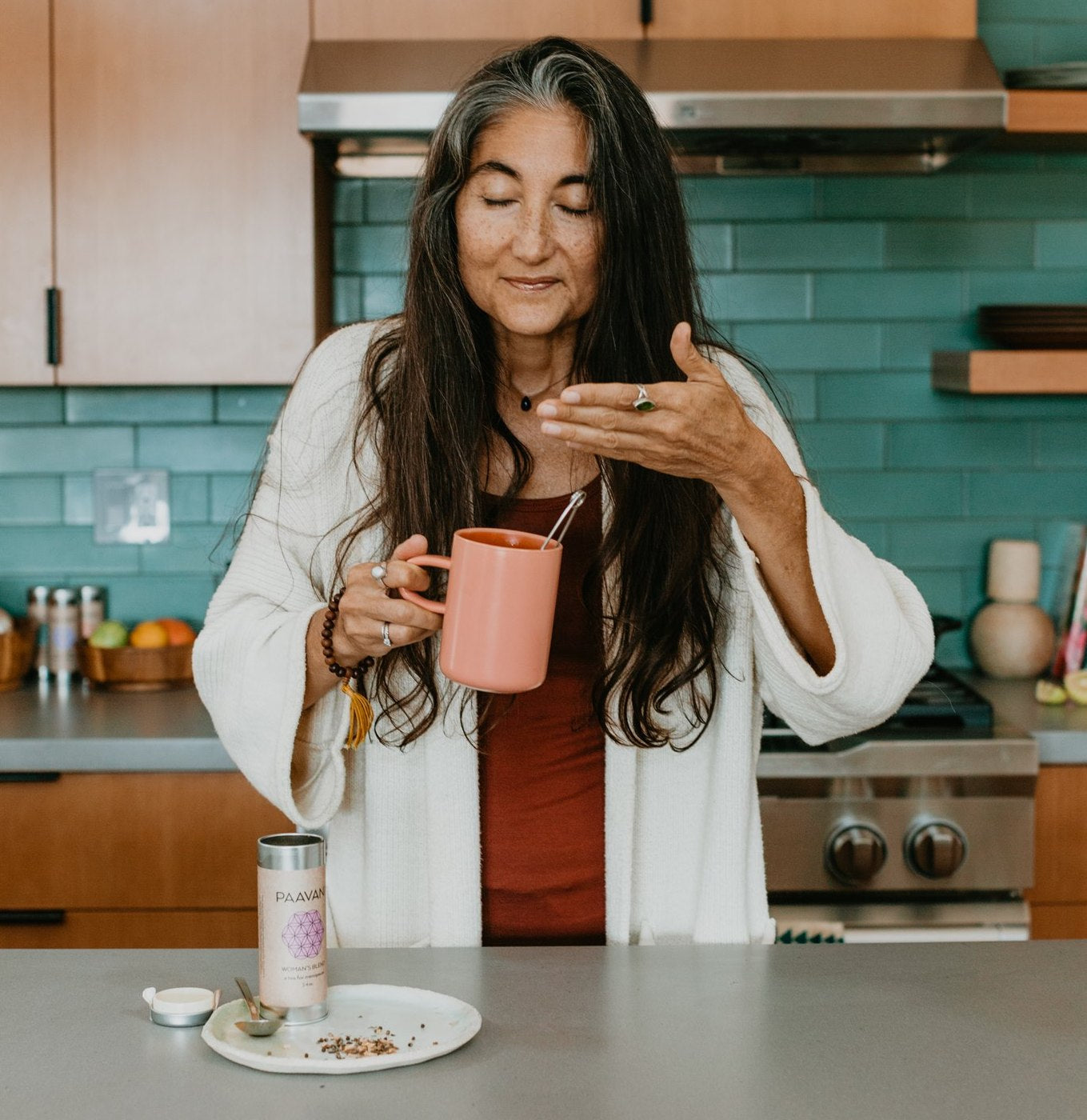 Woman enjoying a cup of ayurvedic tea for hormonal balance in a modern kitchen setting